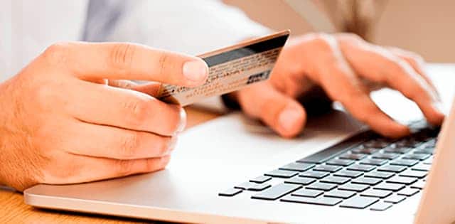Person sidder foran sin computer med et kreditkort i hånden og afprøve nogle af vores ekstra webshop-funktioner